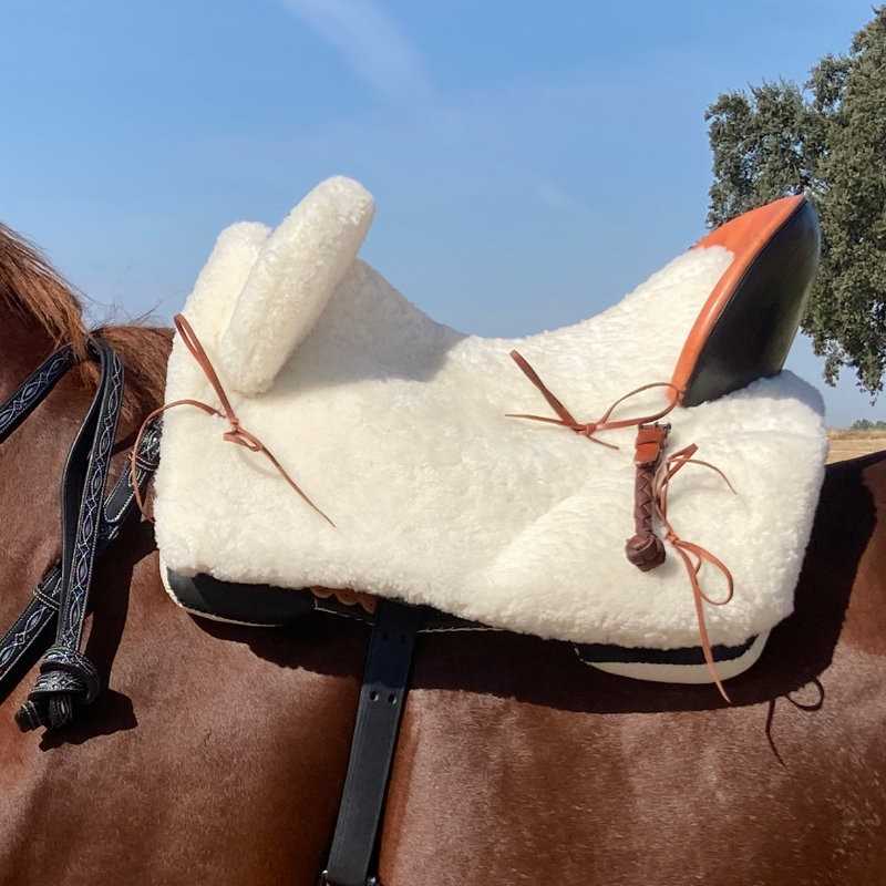 Sela de cavalo em tecido peludo branco com detalhes em couro e alças sobre cavalo castanho