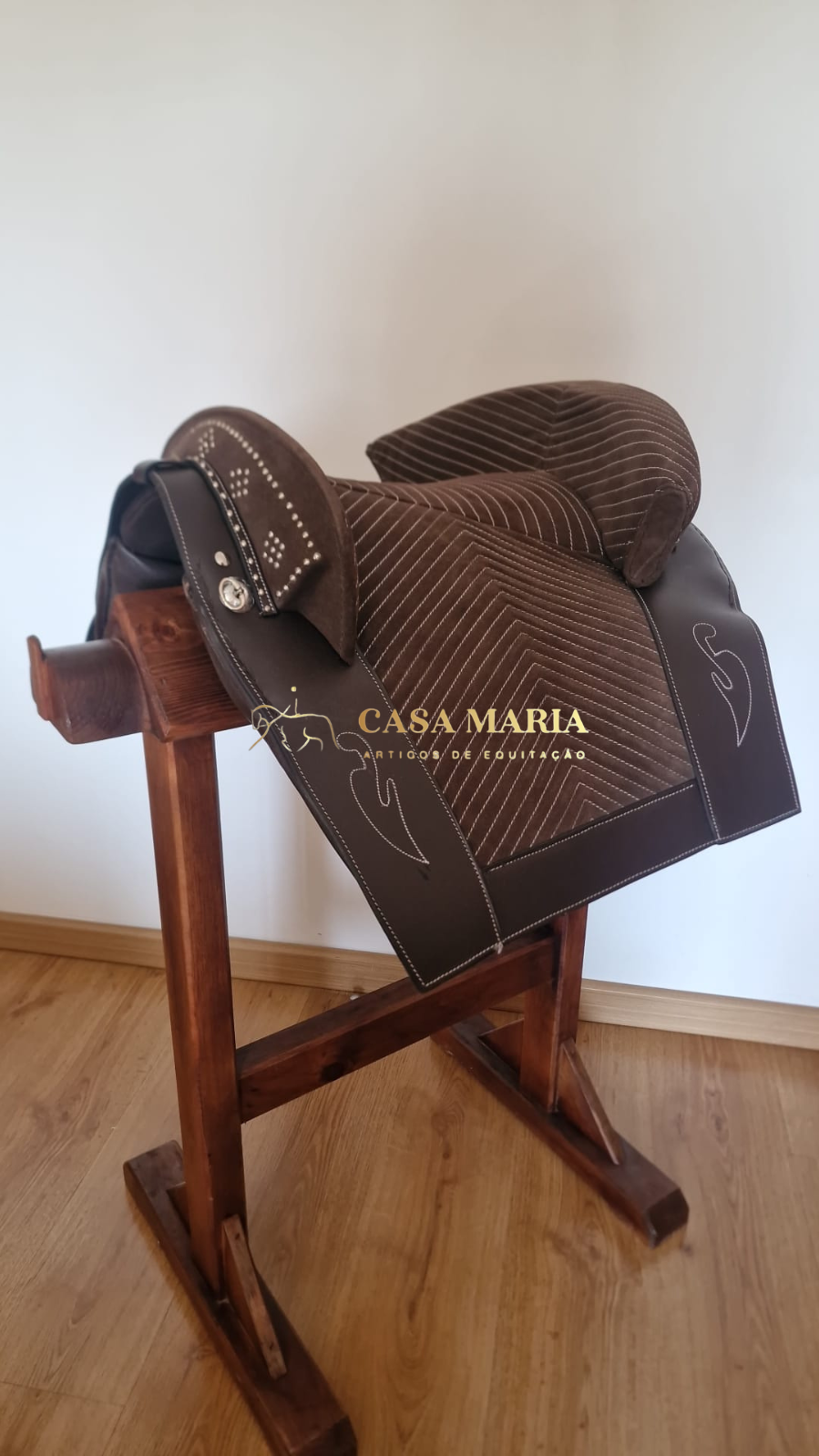 Sela de equitação castanha de couro e camurça num suporte de madeira