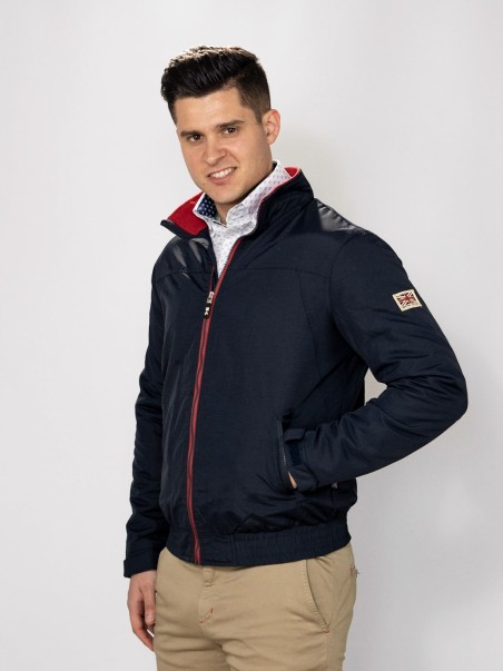 Homem a usar casaco azul escuro com zíper vermelho, gola vermelha e bolso lateral