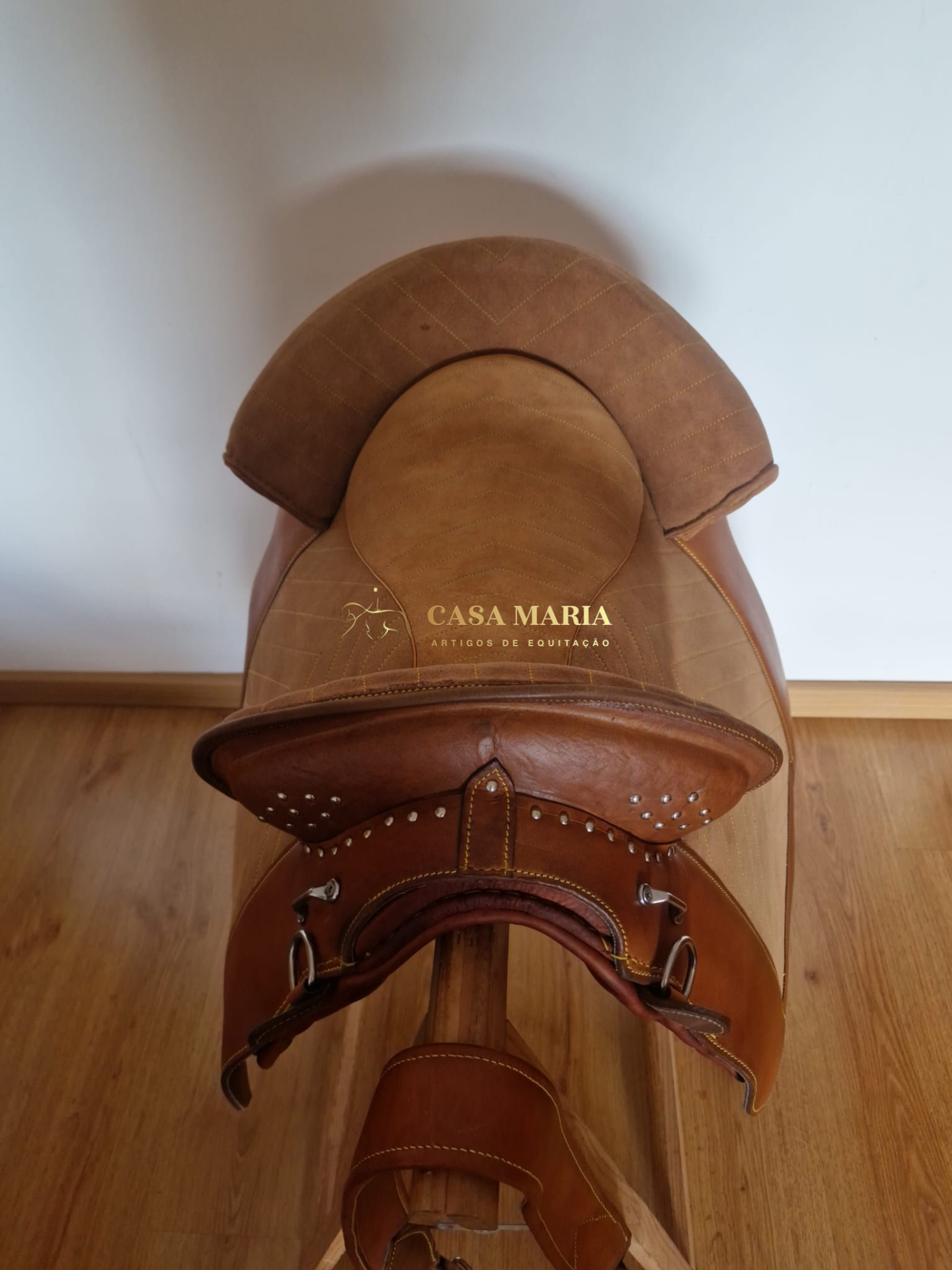 Sela de couro castanho claro e escuro com inscrição 'CASA MARIA ARTIGOS DE EQUITAÇÃO'
