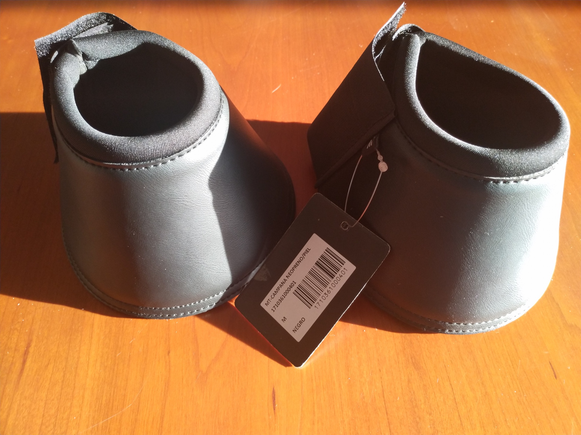 Protetores para cascos de cavalo negros com etiqueta e código de barras sobre madeira