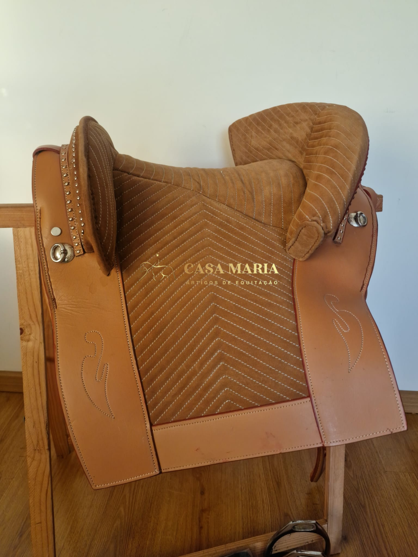 Sela castanha clara em couro com acolchoamento riscado e texto CASA MARIA