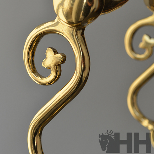 Detalhe de candeeiros dourados com design curvo e trevo decorativo