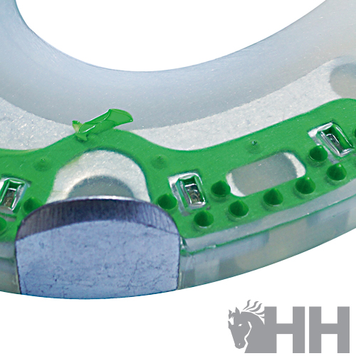 Dispositivo circular transparente com componentes electrónicos verdes e metalizados, fundo branco, logótipo HH cinzento