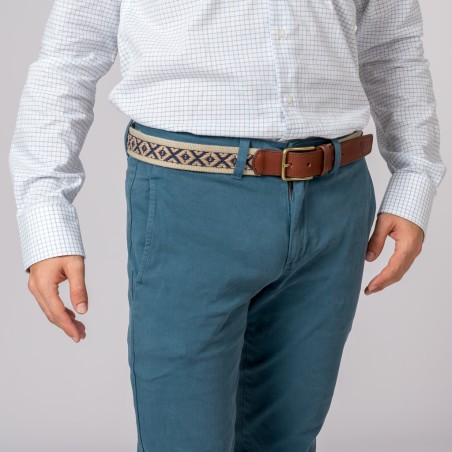 Homem com camisa branca xadrez e calças azuis com cinto castanho e padrão