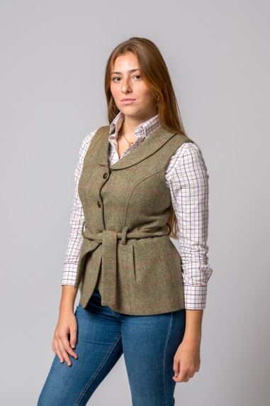 Colete feminino de tweed verde com cinto e botões, camisa quadriculada branca e castanha, jeans azul