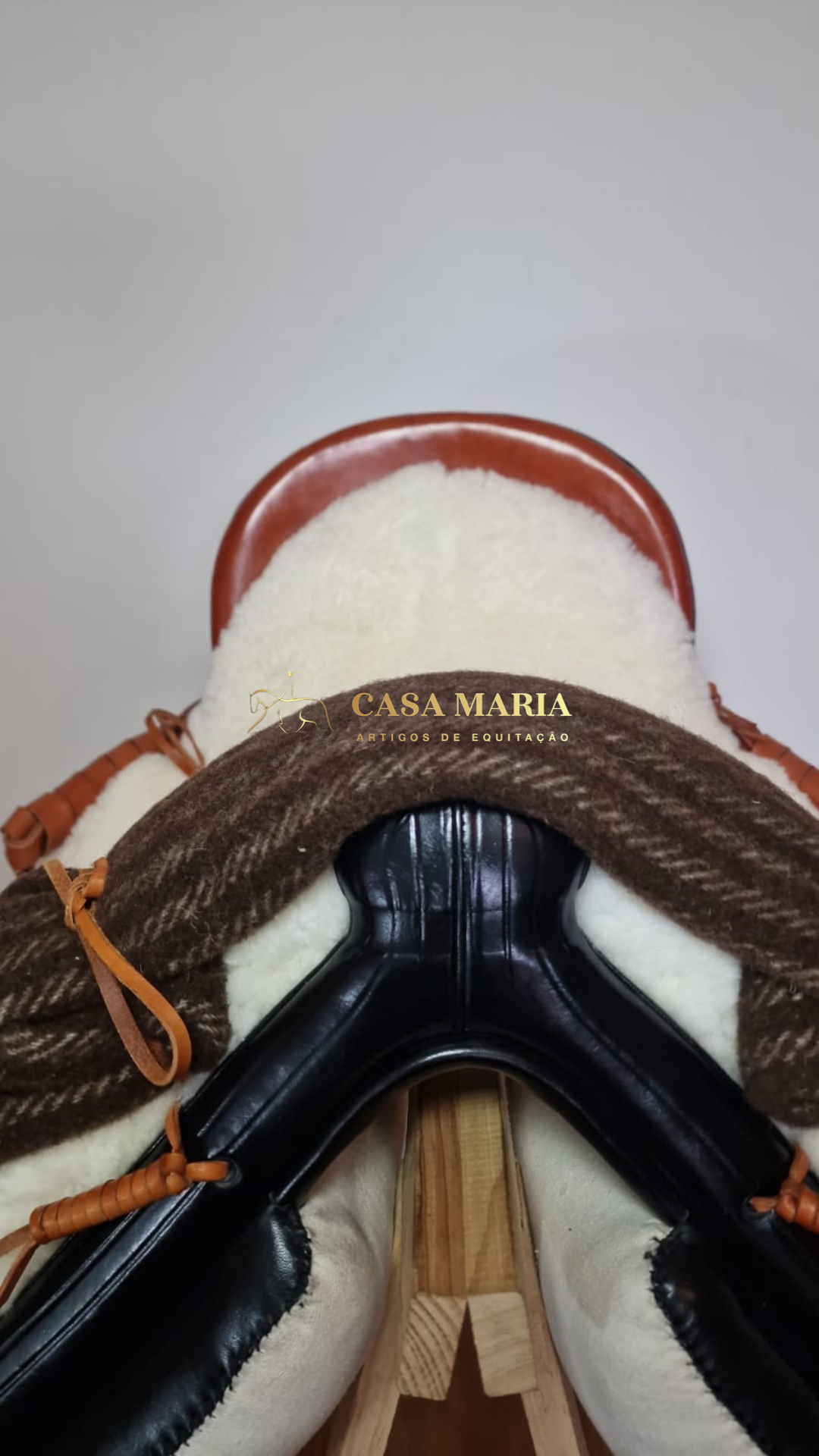 Sela de equitação castanha e preta com acolchoamento branco, ensaio próximo