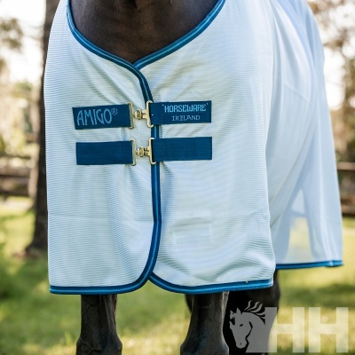 Cobertura branca para cavalo com contornos azuis e etiquetas com texto, num cavalo ao ar livre