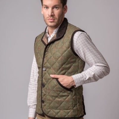 Homem a usar colete acolchoado verde e camisa branca de quadrados pequenos
