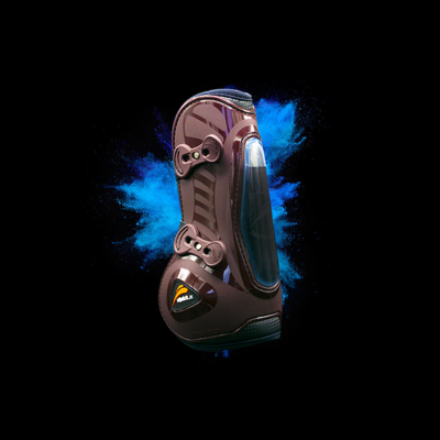 Bota desportiva castanha com fivelas e janela transparente em fundo preto com pó azul.