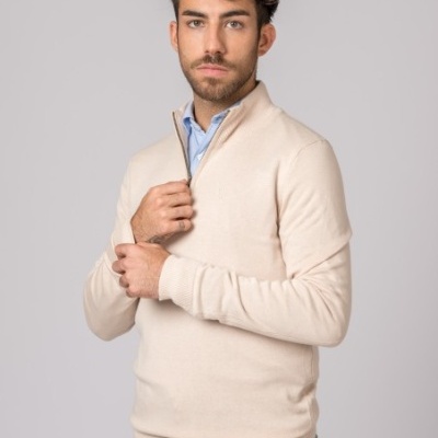 Homem com camisola bege de meia gola e calças de ganga azul