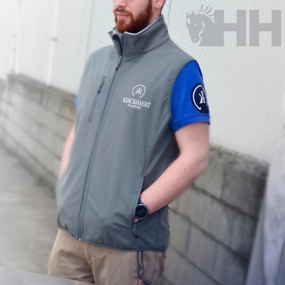 Homem com colete cinzento e t-shirt azul junto a paredes cinzentas