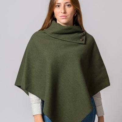 Mulher vestindo poncho verde com botões e camisa branca com padrão de quadrados.