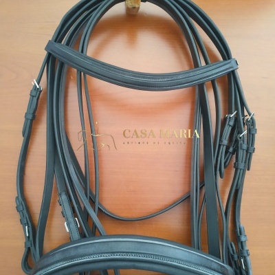 Bridão preto de couro com fivelas metálicas sobre madeira clara com texto CASA MARIA
