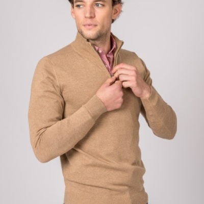 Homem com camisola bege de malha, camisa rosa e calças verdes