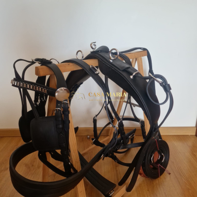 Arreio para cavalo em couro preto com fivelas metálicas sobre suporte de madeira