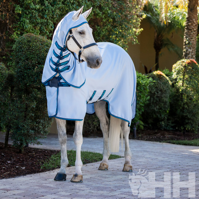 Cavalo branco com manta branca e capuz azul em jardin com arbustos.