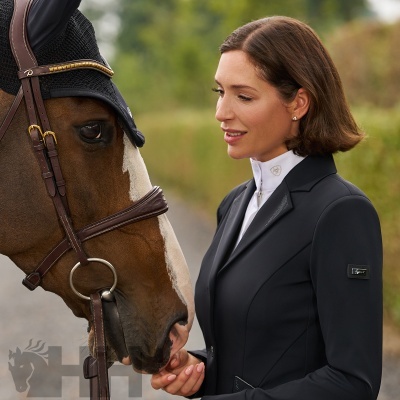 Mulher com casaco de equitação preto e cavalo castanho com touca preta