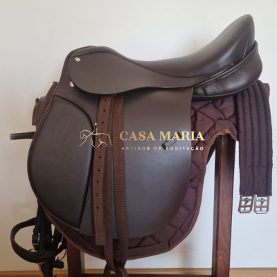 Sela de equitação castanha escura sobre almofada castanha em suporte de madeira