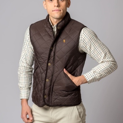 Homem a usar colete acolchoado castanho com camisa xadrez e calças bege