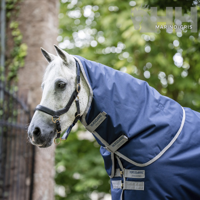 Cavalo branco com manta azul marinho e etiquetas Horseware Ireland em ambiente ao ar livre