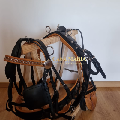 Arnês equino em couro preto e castanho com elementos metálicos em suporte de madeira