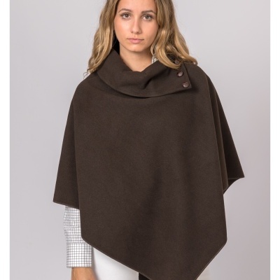 Mulher com capa castanha e camisa branca com padrão de quadrícula