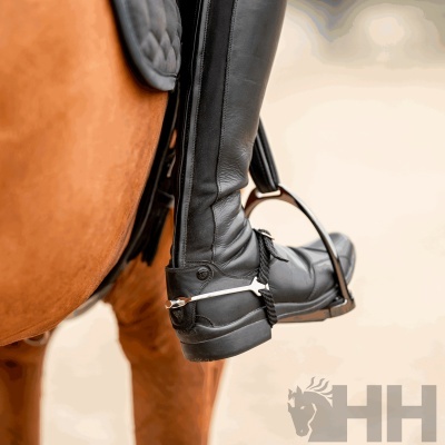 Botas de equitação pretas de couro em estribo de cavalo castanho