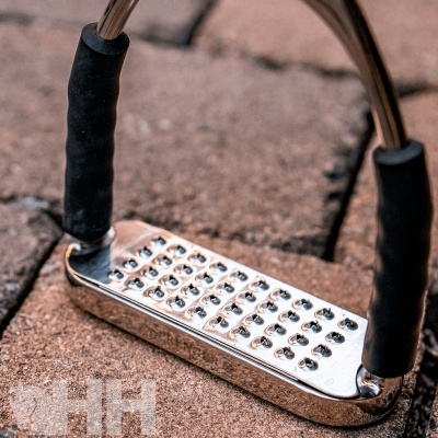 Estribo metálico prateado com apoios pretos em chão de pedra castanha