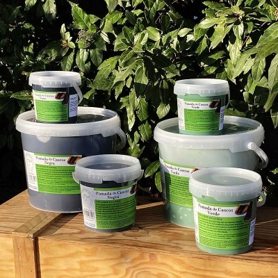 Potes de pomada de cascos em plástico com rótulos verdes em fundo de plantas