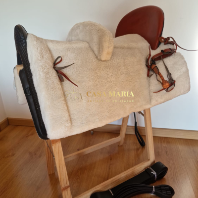 Sela de equitação castanha com revestimento branco em suporte de madeira