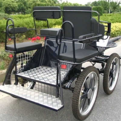 Carroça preta com quatro rodas grandes e assentos de espuma preta na estrada perto de jardim