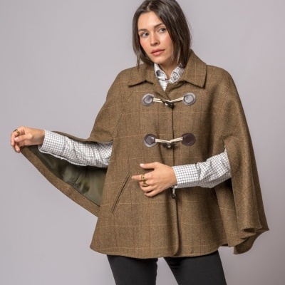 Mulher a usar capa castanha com padrão risca de giz e alamares, com camisa quadriculada branca e cinza.