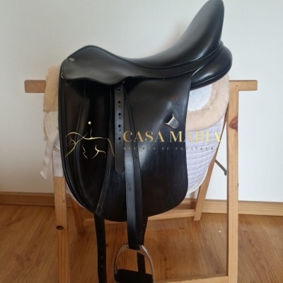 Sela de equitação preta em couro com estribos apoiada em suporte de madeira