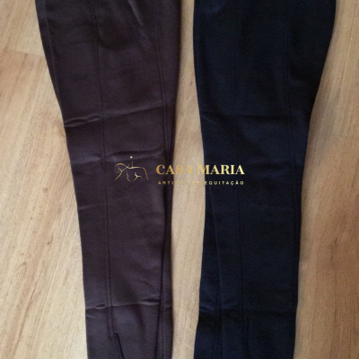 Duas calças de equitação castanha escura e preta, estendidas no chão de madeira