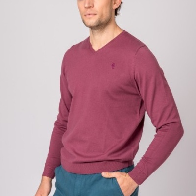 Homem com camisola vinho de malha e calças azuis sobre fundo branco