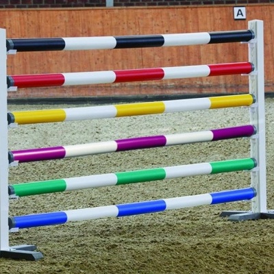 Estrutura de salto de equitação colorida com varões em branco e outras cores, base branca e chão de areia