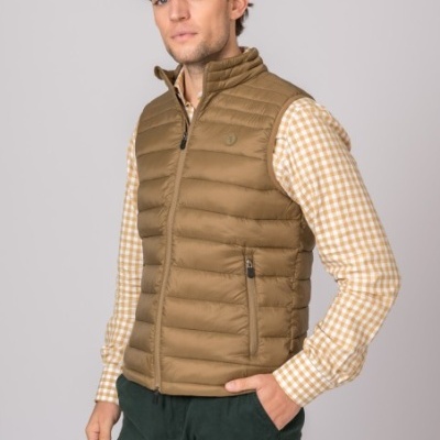 Colete acolchoado castanho com fecho, sobre camisa xadrez bege e branco, calças verdes escuras