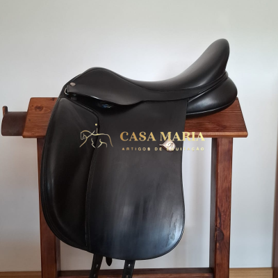 Sela de equitação de pele preta pendurada num suporte de madeira