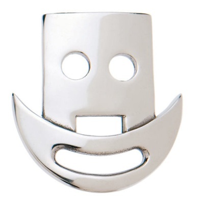 Objeto metálico prateado em forma de face sorridente com dois buracos redondos e recorte inferior