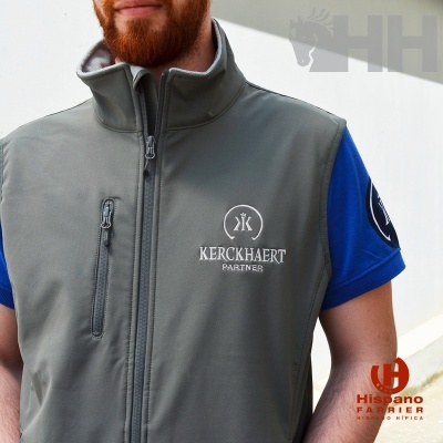 Colete cinza com logo branco KERCKHAERT PARTNER sobre t-shirt azul com logo na manga