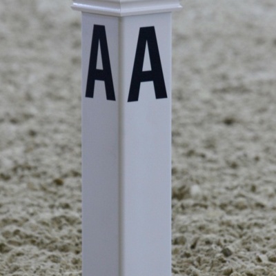 Poste branco com letras AA em superficie de areia clara