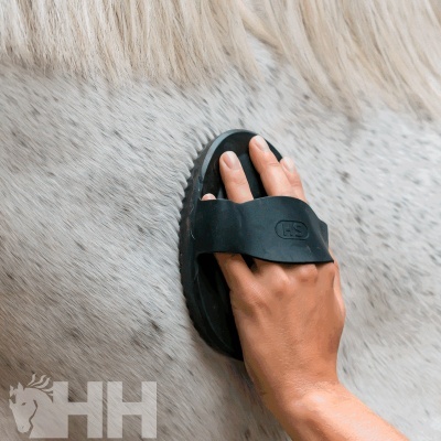 Escova preta para cavalo com design ergonómico sobre pelo claro de cavalo