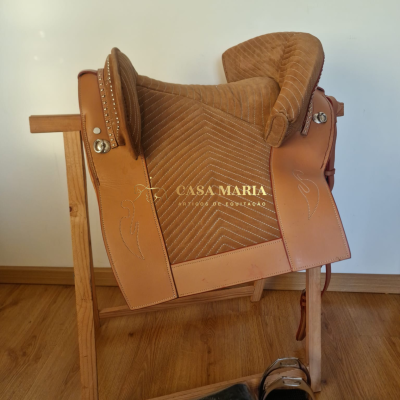 Sela de equitação castanha com acessórios num suporte de madeira