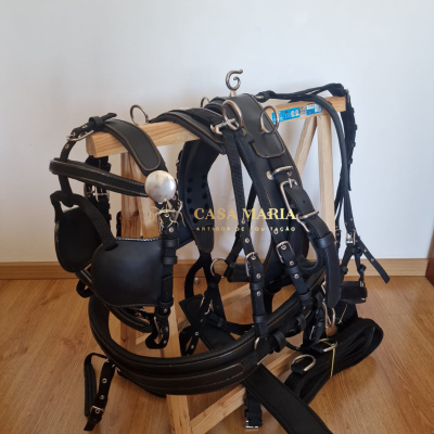 Conjunto de arreios de equitação em couro preto e nylon pendurado num suporte de madeira