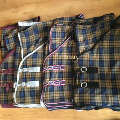 Mantas para cavalos xadrez com cintas e fivelas sobre chão de madeira