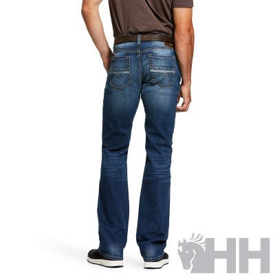 Homem de costas a usar calças de ganga azuis escuras com camiseta castanha e sapatos pretos