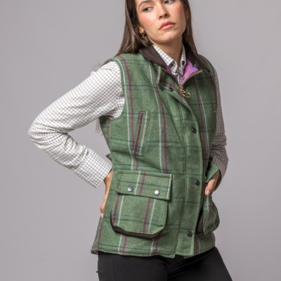 Colete verde às riscas com botões e bolsos, camisa branca e calças pretas, modelo mulher