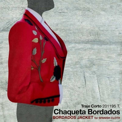 Chaqueta bordada vermelha com bordados florais e pompons em fundo de madeira clara.