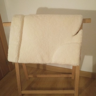 Cobertor de lã bege claro num suporte de madeira